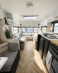 the interior of an rv with wood flooring and white walls, windows, and appliances