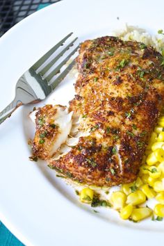 a white plate topped with meat and corn