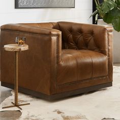 a brown leather chair sitting next to a side table with a glass on top of it