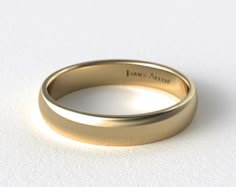 a yellow gold wedding ring on a white surface