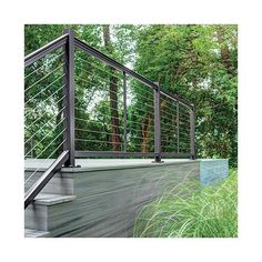 a metal railing on the side of a wooden deck next to tall grass and trees