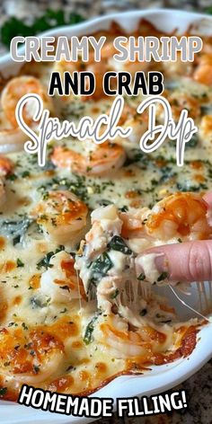 a hand is picking up some shrimp and crab spinach dip from a casserole dish