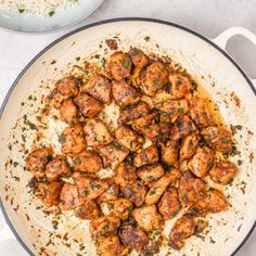 a pan filled with chicken and sauce on top of a table next to a plate