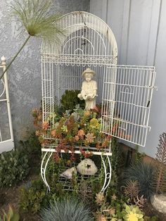 a white birdcage filled with succulents and plants