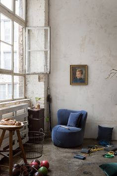 a living room with a blue chair next to a window and other items on the floor