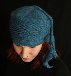 a woman with red hair wearing a blue knitted hat