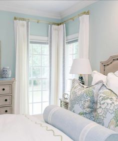 a bedroom with blue walls and white curtains