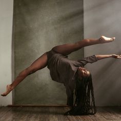 a woman is doing a handstand on the floor in front of a wall