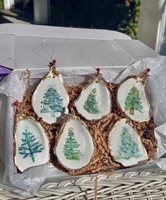 six christmas ornaments in a box on a table with some string and beads hanging from them