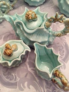 there are many blue dishes on the table together, including one with seashells in it