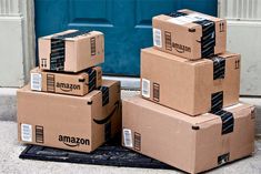 three boxes stacked on top of each other in front of a blue door with the amazon logo