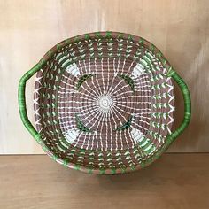 a brown and green basket sitting on top of a wooden table