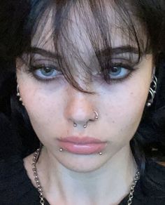 a close up of a person with piercings on her nose and nose chain around their neck