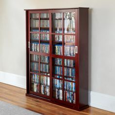 a book case with many books in it on the floor next to a rug and window