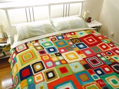 a bed covered in a colorful blanket and pillows