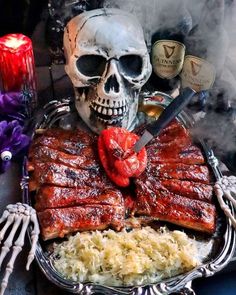 a plate with ribs, rice and meat on it next to a skull holding a knife