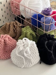 several crocheted bags and balls of yarn in a basket on a table top