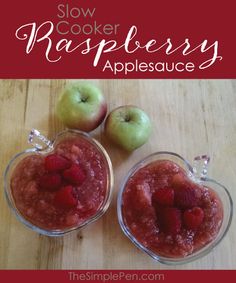 two small bowls filled with raspberries and apples on top of a wooden table