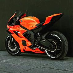 an orange motorcycle parked next to a black wall