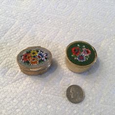 two small metal boxes sitting on top of a white blanket next to a penny coin