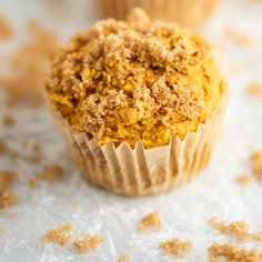 two muffins sitting on top of a white table covered in crumbs