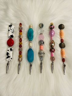 several different types of beaded items are arranged on a white fur covered surface,