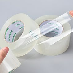 two rolls of clear tape being held by someone's hand