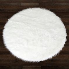 a round white rug on top of a wooden floor