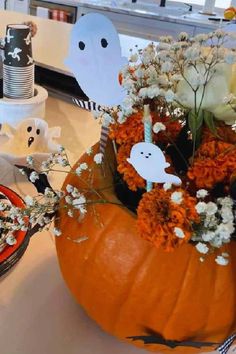 a decorated pumpkin sitting on top of a table next to a plate with flowers and ghost decorations