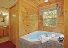 a bathroom with a large jacuzzi tub in the corner and wood paneling on the walls