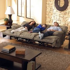 three people laying on a couch in a living room