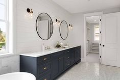 a bathroom with two sinks and three mirrors on the wall next to a bathtub