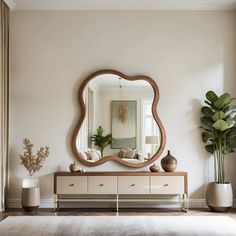 a large mirror sitting on top of a dresser next to a vase and potted plant