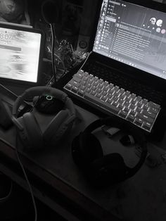 a laptop computer sitting on top of a desk next to a mouse and headphones