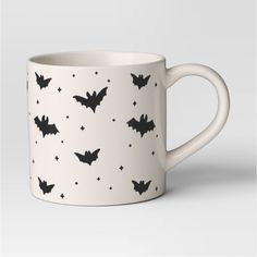 a white coffee mug with bats on the side and stars all over it's surface