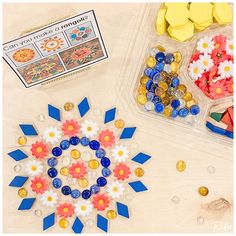 an assortment of colorful beads and other crafting supplies on a table with paper flowers