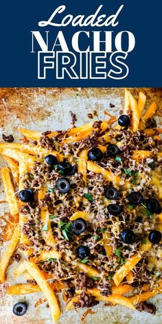 loaded nacho fries with cheese and black olives on a sheet of parchment paper