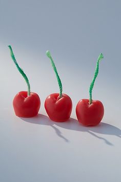 three cherries with green stems on a white surface