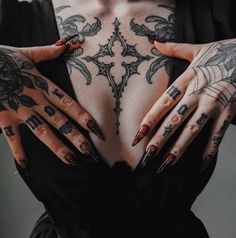 a woman with tattoos on her chest and hands behind her are both wearing red fingernails