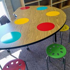 a wooden table topped with four colorful chairs