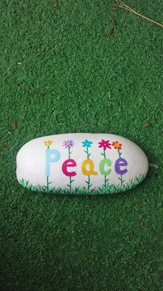 a rock with the word peace painted on it sitting in grass next to a string