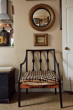 a chair sitting in front of a wall with pictures on it and a mirror above it