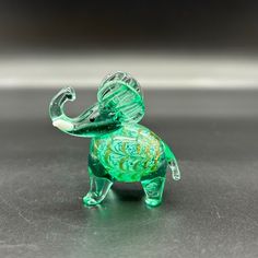 an elephant glass figurine sitting on top of a black table next to a white wall