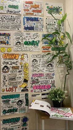 a wall covered in lots of stickers next to a potted plant on top of a table