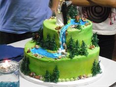 a green cake with trees on it and a stream coming out of the top layer