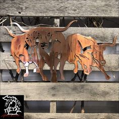 three metal cows are standing on a wooden bench