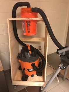 an orange and black vacuum is in a cabinet