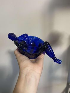 a hand is holding a blue glass sculpture