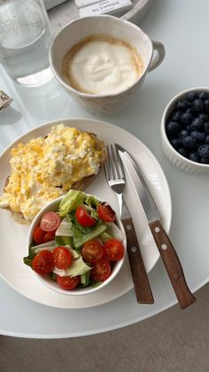 a white plate topped with food next to a bowl of salad