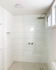 a white tiled bathroom with a shower head